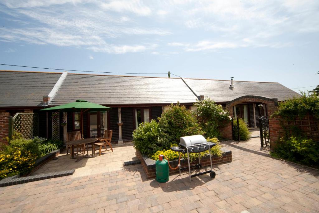 eine Terrasse mit Grill und ein Haus in der Unterkunft Newclose Farm Cottages in Yarmouth