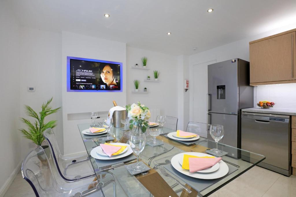 ein Esszimmer mit einem Glastisch und eine Küche in der Unterkunft Spacious 4BR City Centre Apartment w/ Free Parking in Edinburgh