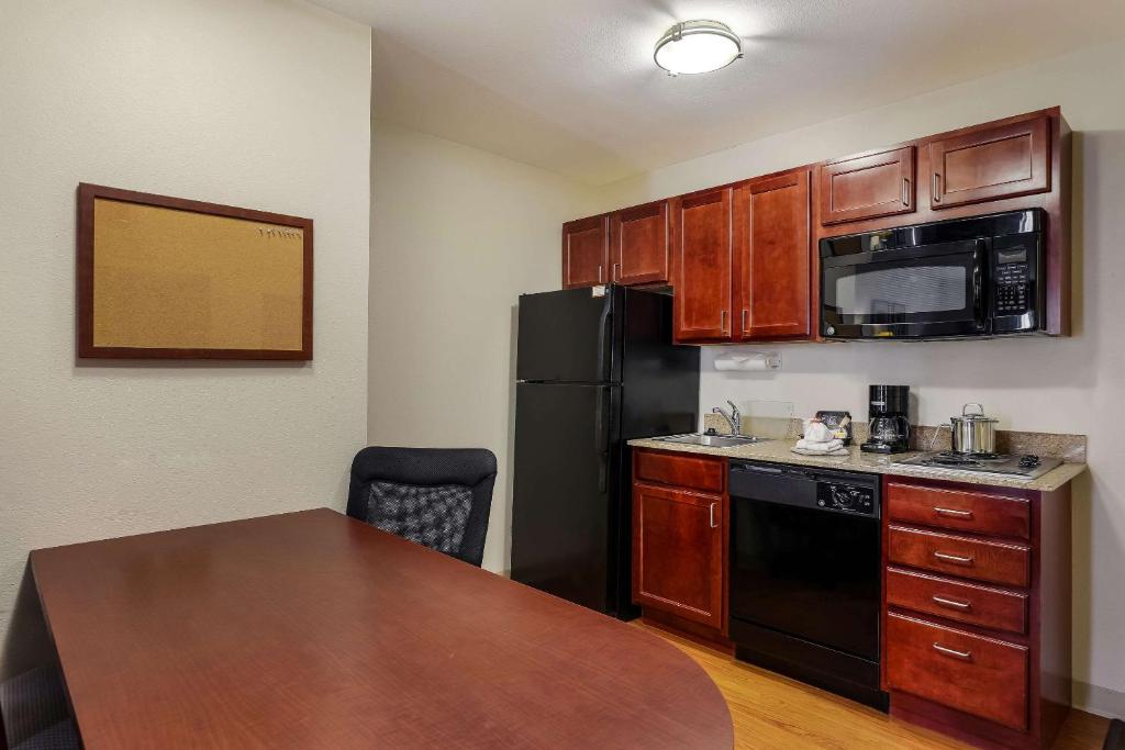 a kitchen with a black refrigerator and a table at MainStay Suites Fitchburg - Madison in Madison