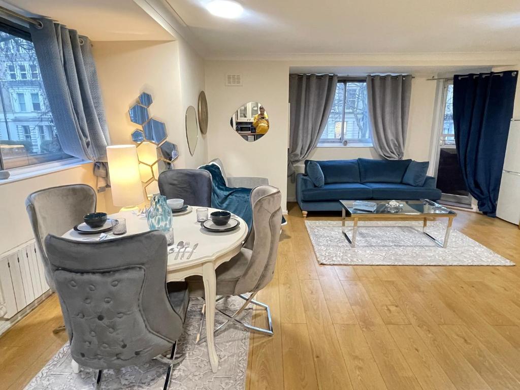 ein Wohnzimmer mit einem Tisch und einem blauen Sofa in der Unterkunft The Sherborne Residence in London