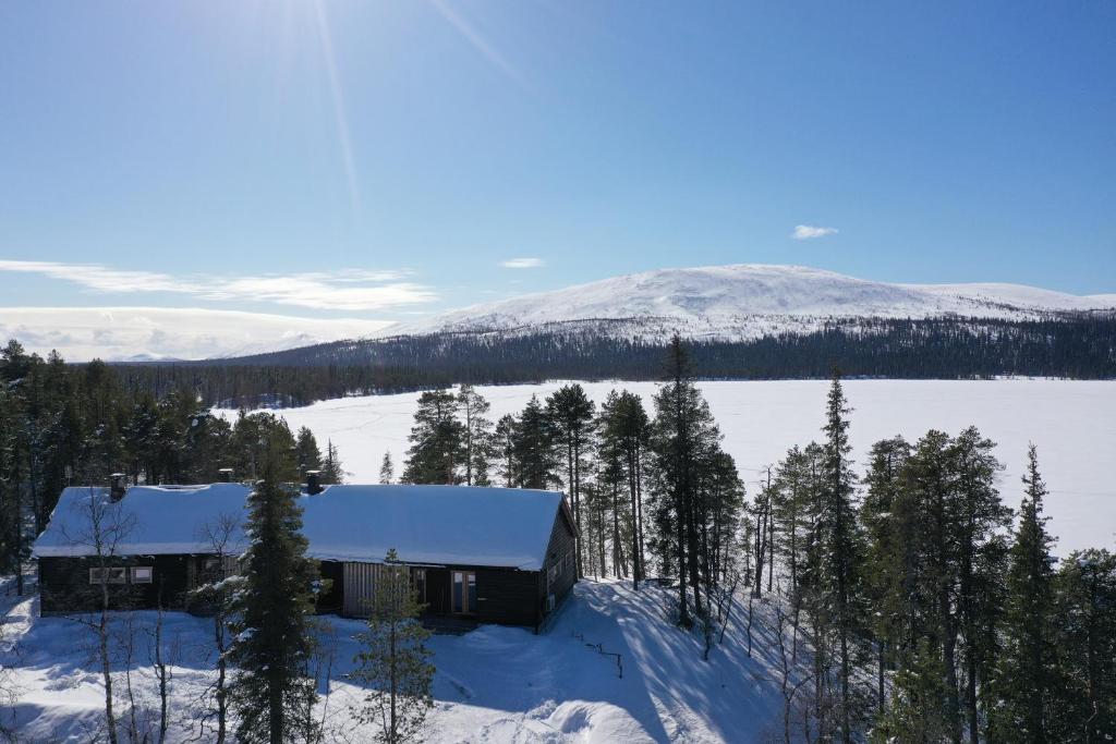 eine Hütte im Schnee mit Bäumen und einem Berg in der Unterkunft Villa Northern Lights by DG Lomailu, Lapland, Finland in Kyrö