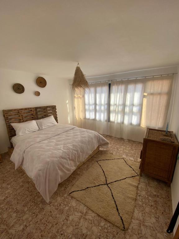 a bedroom with a bed and a table and windows at Sable beach surf camp taghazout in Taghazout