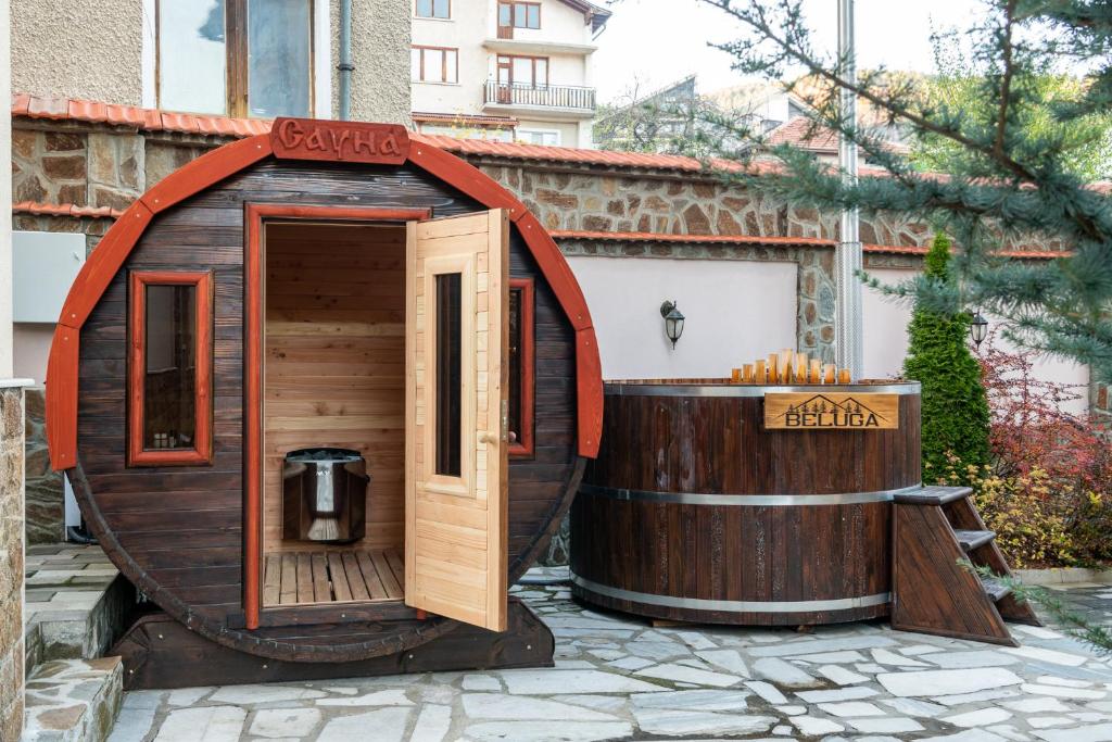 a small sauna and a hot tub next to a building at Beluga Guest House in Velingrad