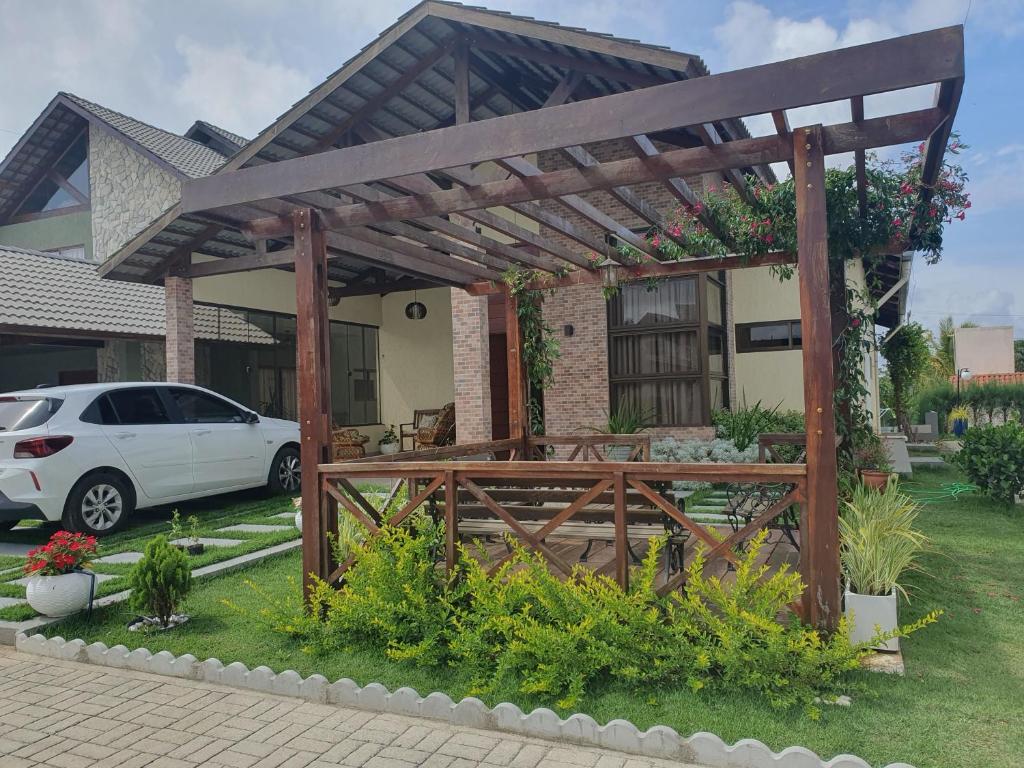 a wooden pergola in front of a house at Chalé de campo em condomínio fechado in Bananeiras