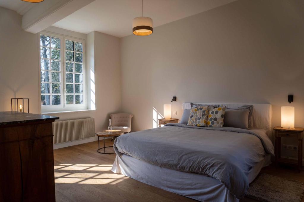 a bedroom with a large bed and a window at Les Suites Château du Breuil Normandie in Le Breuil-en-Auge