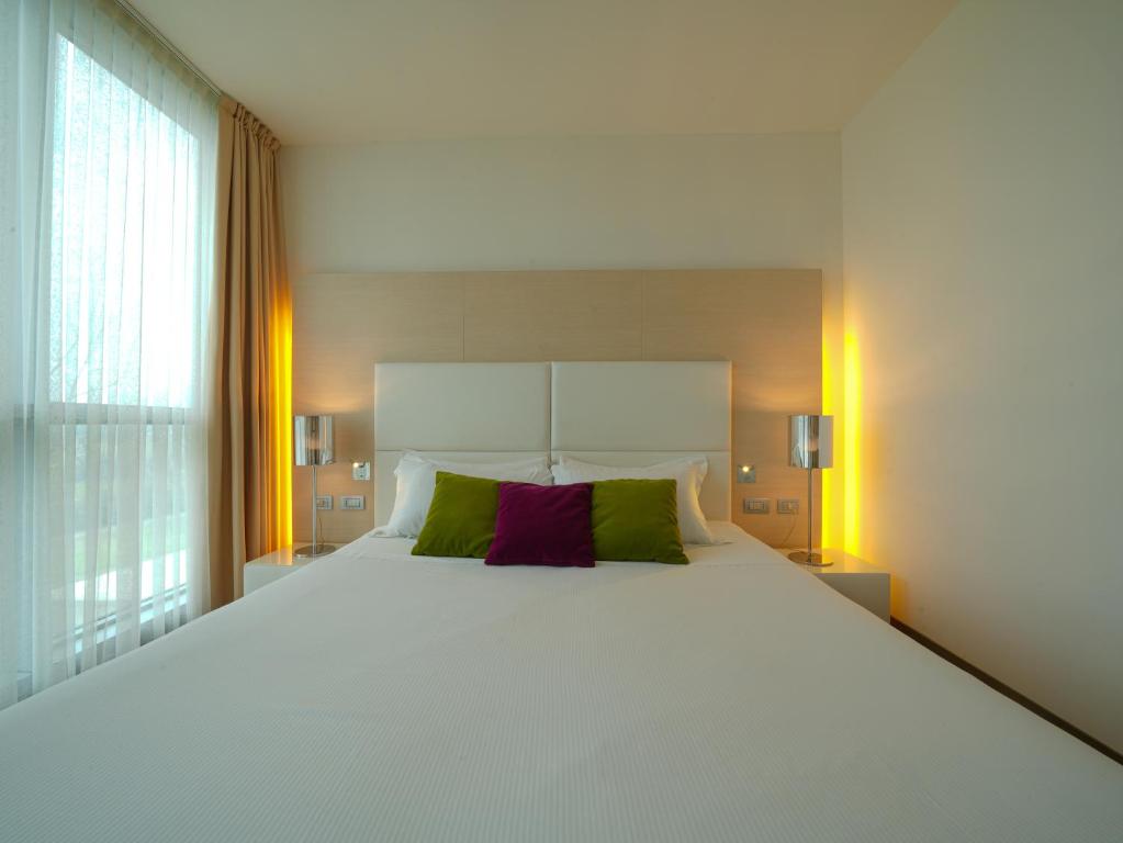 a large white bed with green and purple pillows at Pisa Tower Plaza in Pisa