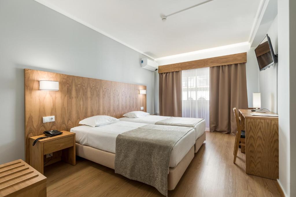 a hotel room with a large bed and a television at Hotel Moinho De Vento in Viseu