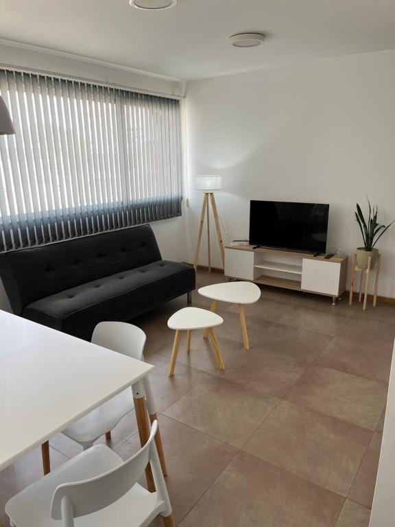 a living room with a couch and tables and a tv at Temporario La Plata2 in La Plata