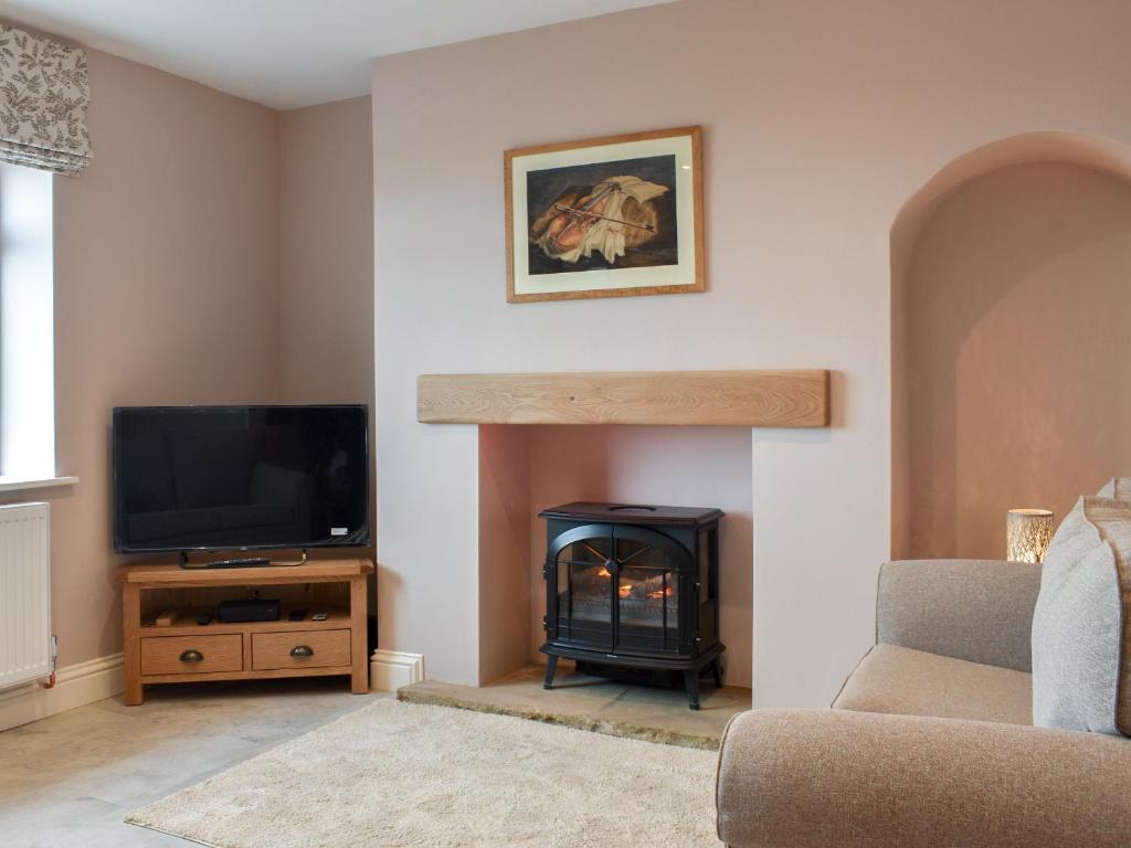 sala de estar con chimenea y TV en Cremona Cottage, en Carlin How