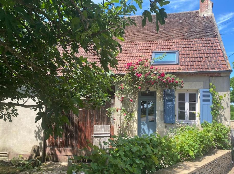 a small house with flowers on the front of it at Chez Trudi Charmante maison à la campagne in Livry