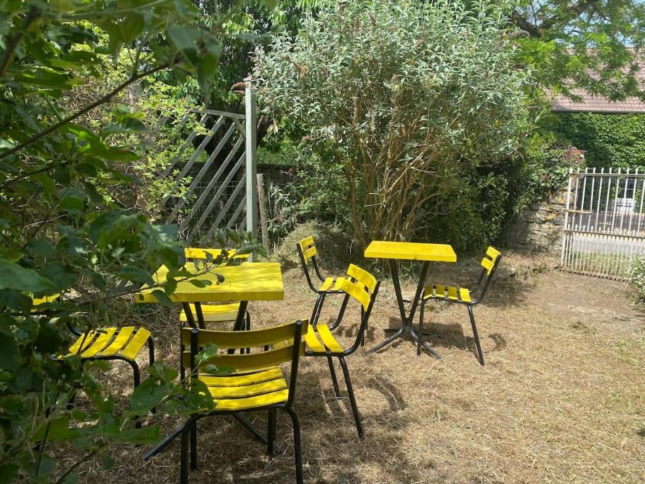 a group of yellow tables and chairs in a yard at Chez Trudi Charmante maison à la campagne in Livry