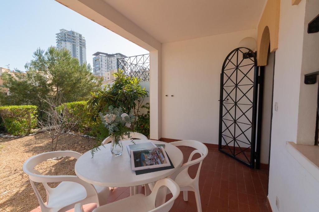 una mesa y sillas blancas en una habitación con ventana en Bungalows Aparto Residence Galetamar, en Calpe