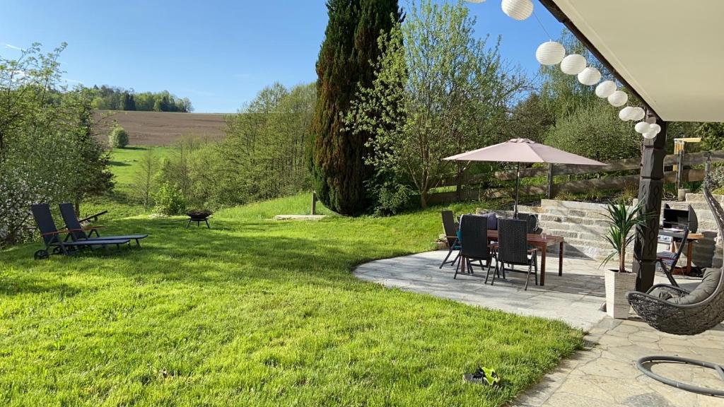 eine Terrasse mit einem Tisch, Stühlen und einem Sonnenschirm in der Unterkunft Ferienwohnung Elisa in Tiefenbach