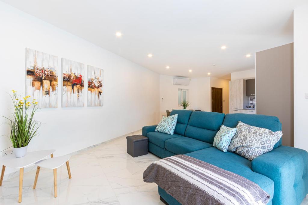 - un salon avec un canapé bleu et une table dans l'établissement H1- Modern & Spacious 3 Bedroom Apartment, à San Ġwann
