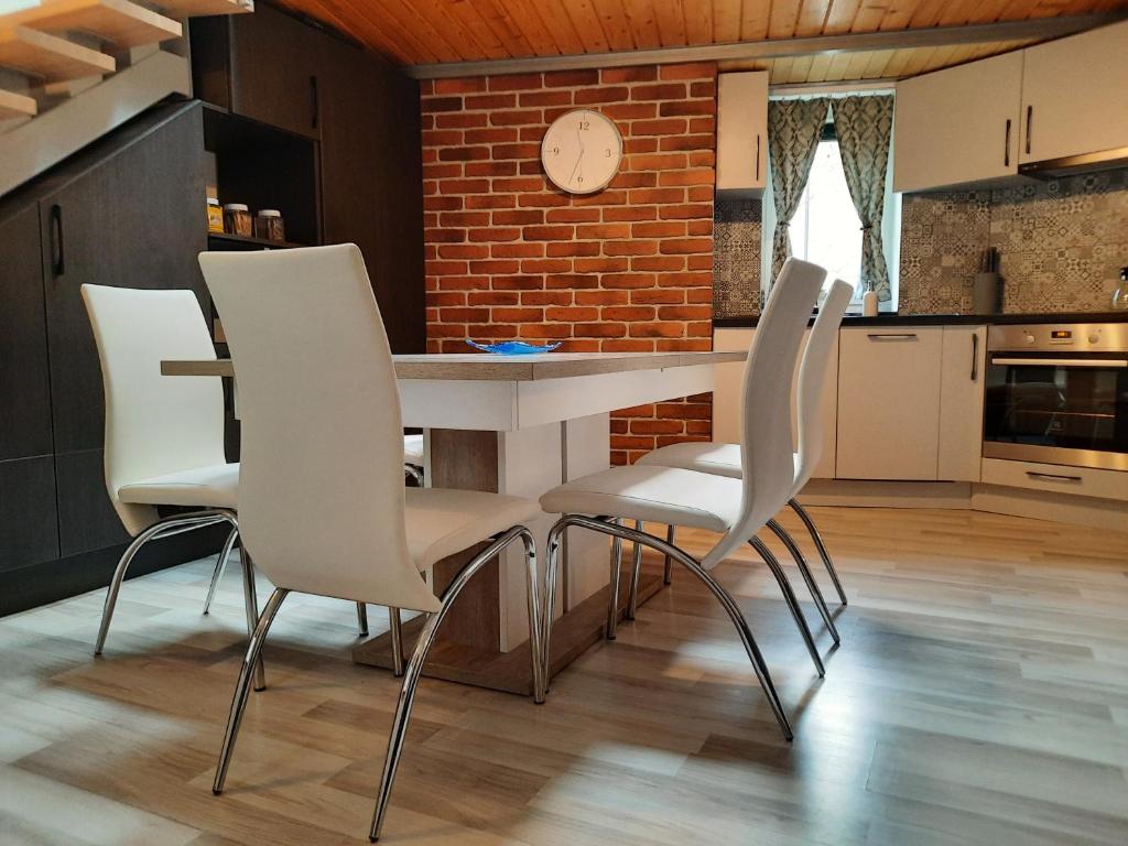 a kitchen with white chairs and a table and a brick wall at Exclusive Art Apartment in Krakow