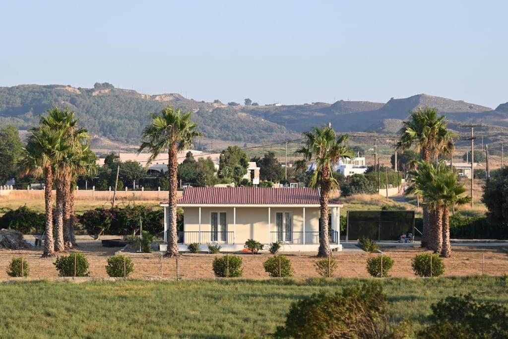 a house with palm trees in front of a field at Beachlife: The Bungalow in Kos Town