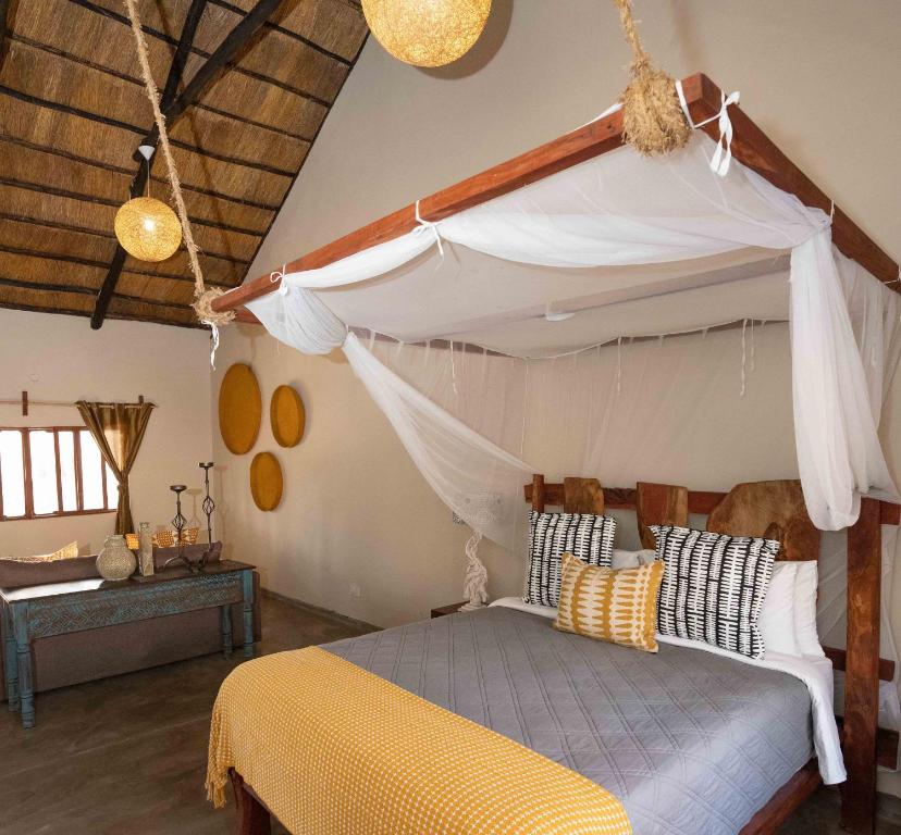 a bedroom with a bed with a canopy at Gwango Elephant Lodge in Dete