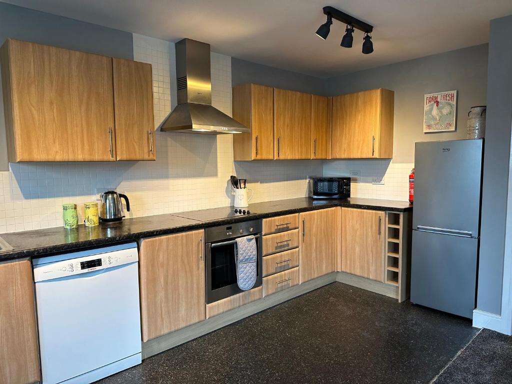 uma cozinha com armários de madeira e um frigorífico branco em Stylish 2 Bed Apartment Derby em Derby