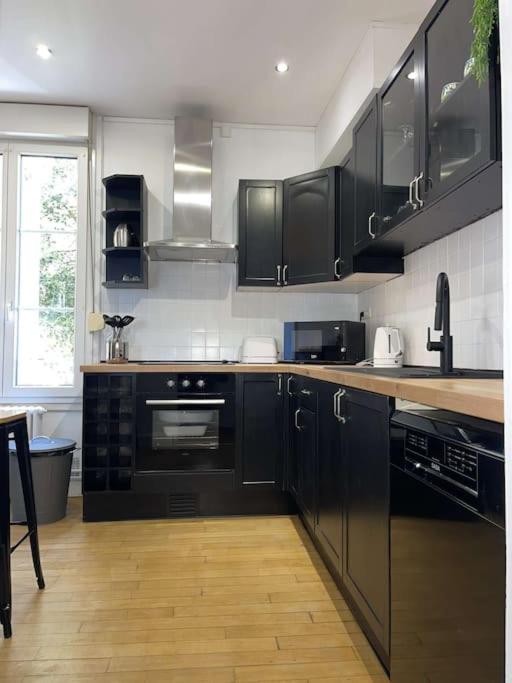 a kitchen with black appliances and a wooden floor at En_Terre_Champenoise Epernay in Épernay