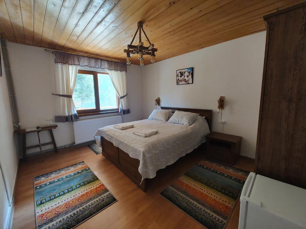 a bedroom with a bed and a wooden ceiling at SEZATOAREA LUPILOR in Lepşa