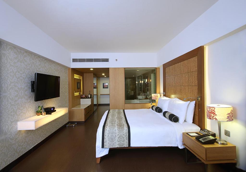 um quarto de hotel com uma cama grande e uma televisão em Fortune Select SG Highway, Ahmedabad - Member ITC's Hotel Group em Ahmedabad