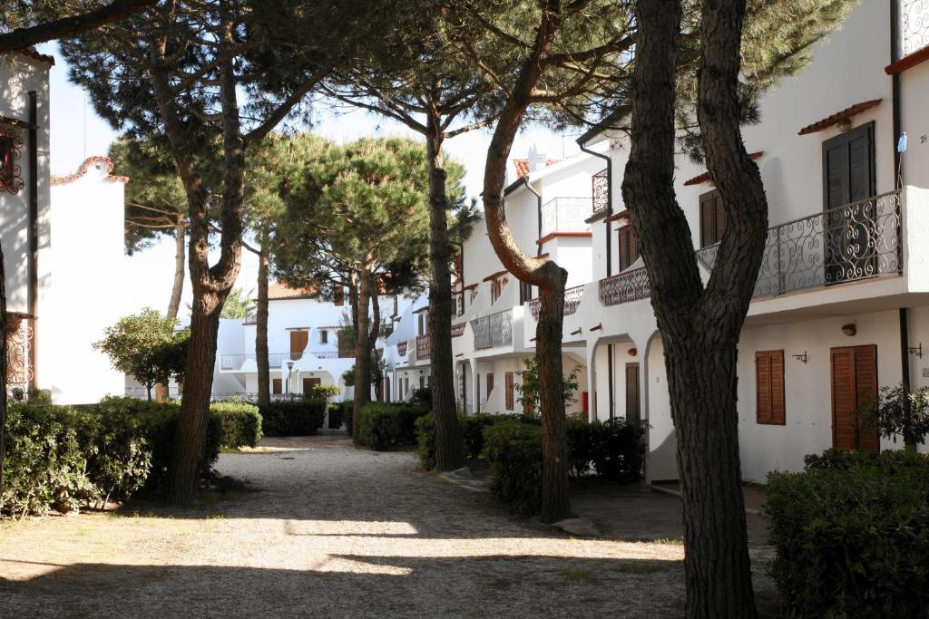 eine Reihe von Bäumen vor einem weißen Gebäude in der Unterkunft Residence El Patio in Rosolina Mare