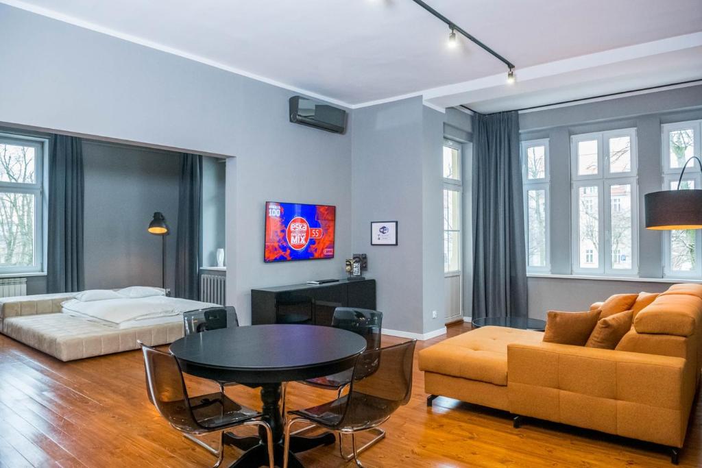 - un salon avec un canapé, une table et un lit dans l'établissement AH Apartamenty - Park, à Ełk