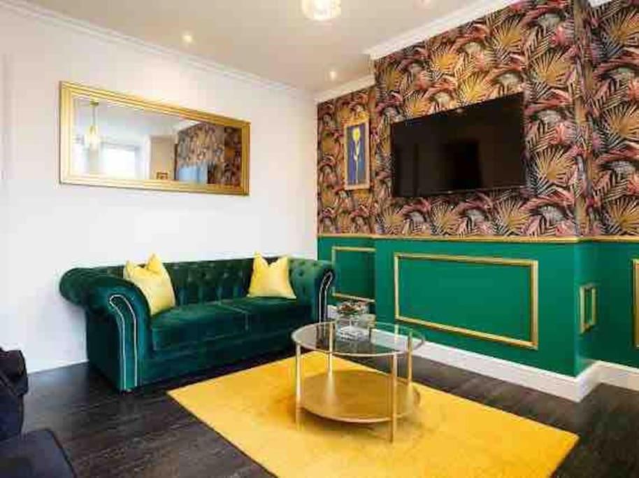 a living room with a green couch and a tv at Luxury 2 Bedroom Home in Leeds