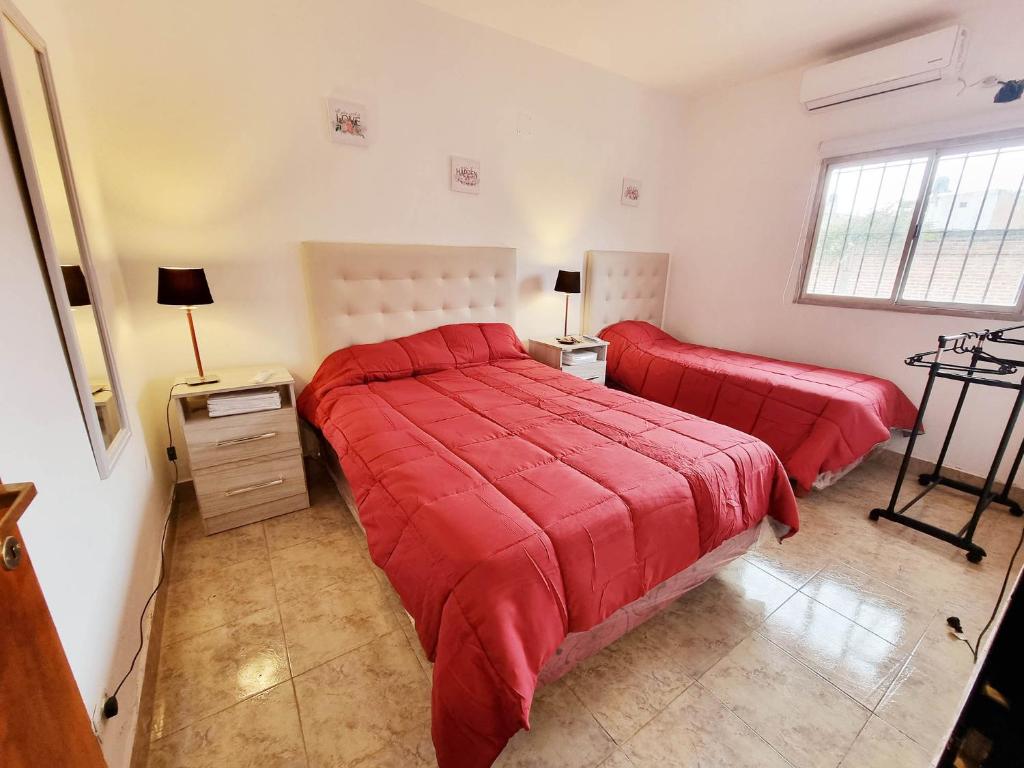 1 Schlafzimmer mit 2 Betten mit roter Bettwäsche und einem Fenster in der Unterkunft Lindo departamento en planta baja en Jujuy in San Salvador de Jujuy