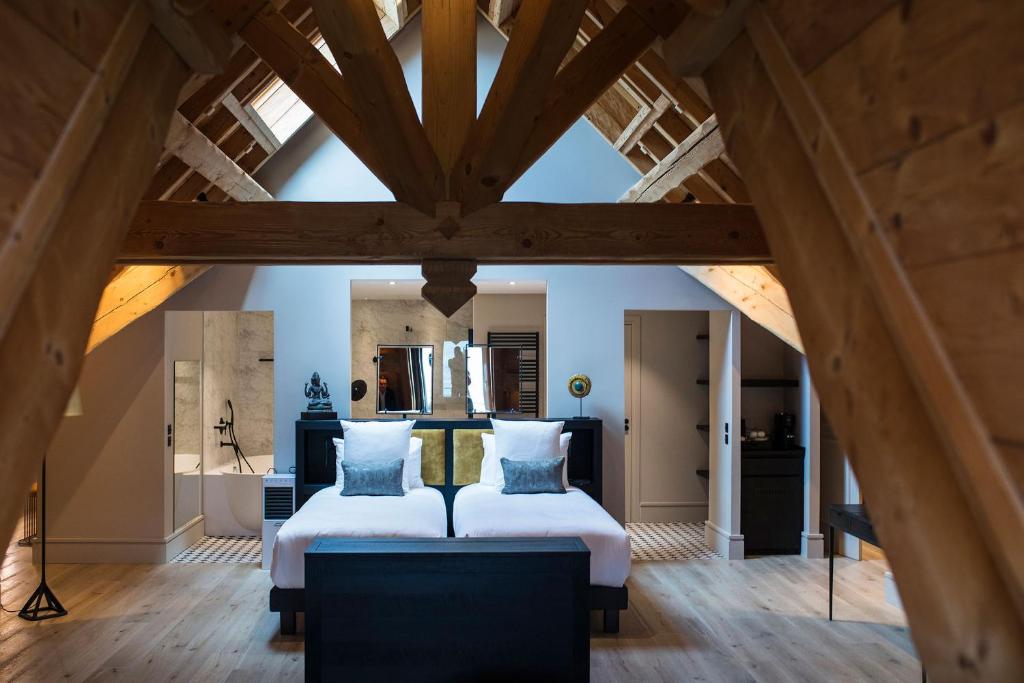 two beds in a room with wooden ceilings at Hôtel L'Incomparable & Restaurant Etoilé Aix-Les-Bains in Tresserves