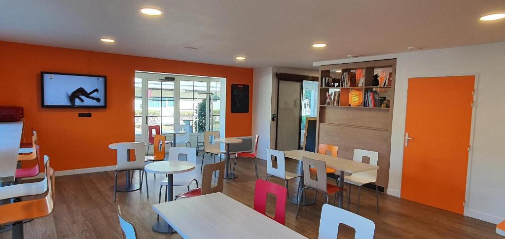 a restaurant with tables and chairs and a tv on the wall at Première Classe Nantes Sud - Rezé Aéroport in Rezé