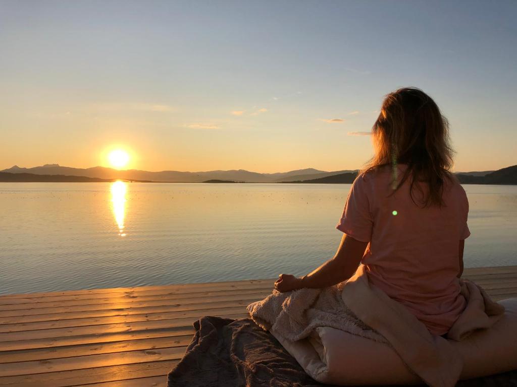 a woman sitting on a dock watching the sunset at Attme Have 