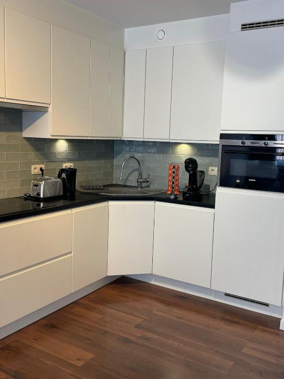 a kitchen with white cabinets and black counter tops at Marktplein Middelkerke in Middelkerke