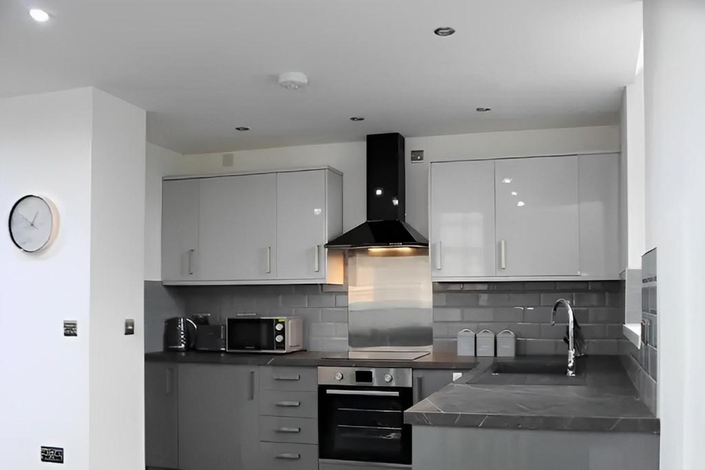 a kitchen with white cabinets and a sink at Contemporary Comfort - Central Bradford Flat in Bradford