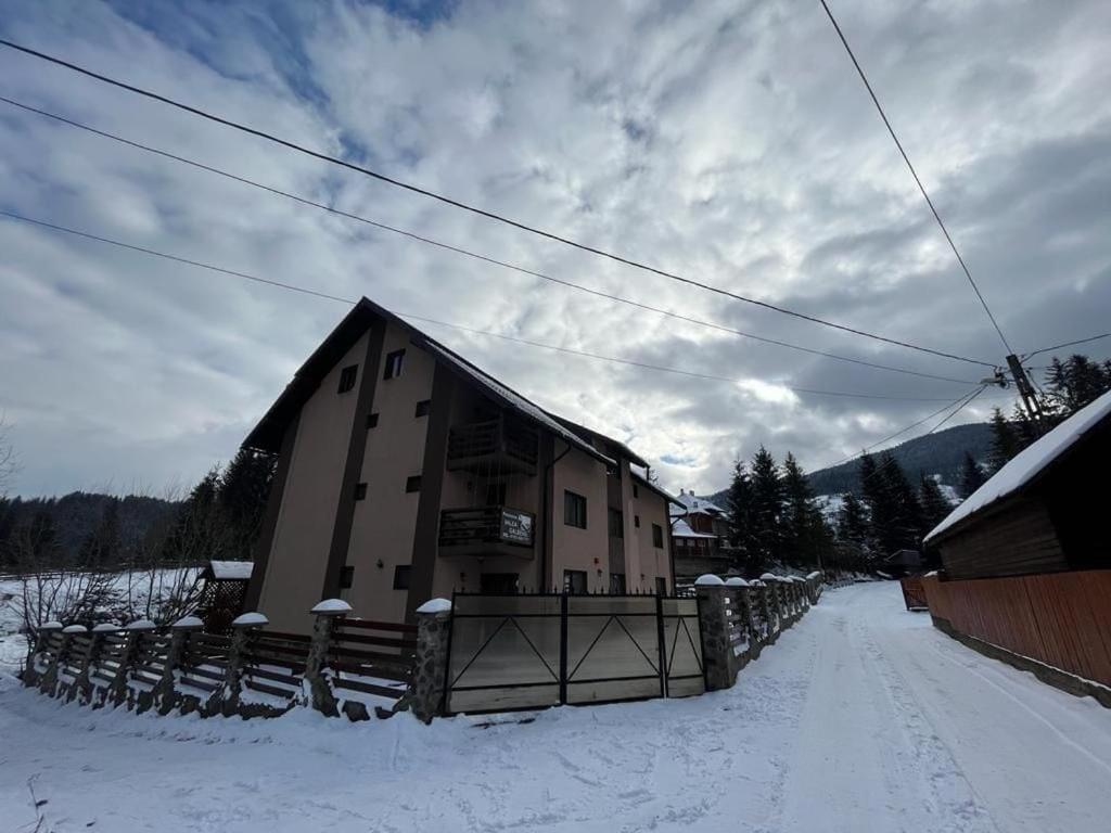 un bâtiment dans la neige à côté d'une clôture dans l'établissement Pensiunea Valea Galbenei, à Arieşeni