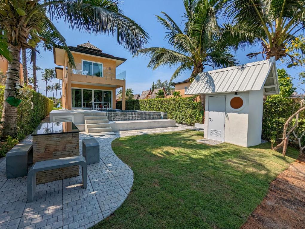 une arrière-cour avec des palmiers et une maison dans l'établissement Blue Cove Pool Villa, à Trat