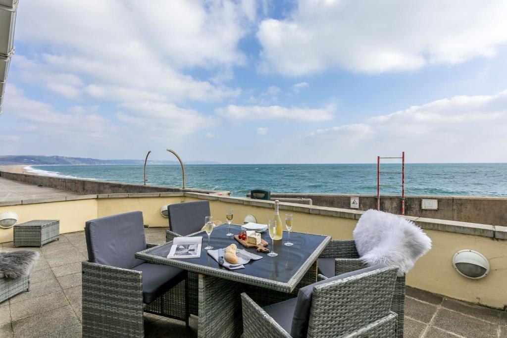 a table and chairs on a patio overlooking the ocean at 3 At The Beach, Torcross in Beesands
