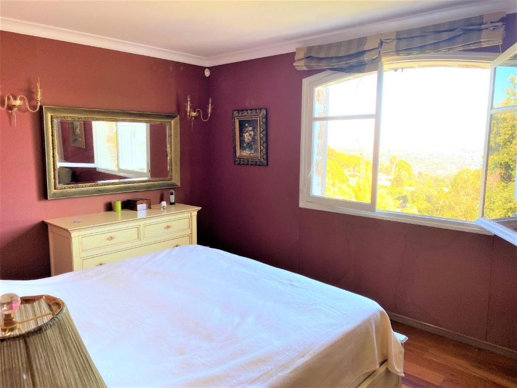 a bedroom with a white bed and a window at VILLA LE MAS D&#39;AZUR BY ESTATESCANNES in Vallauris