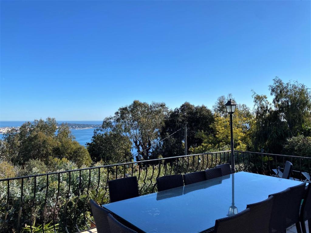 a table on a balcony with a view of the water at VILLA LE MAS D&#39;AZUR BY ESTATESCANNES in Vallauris