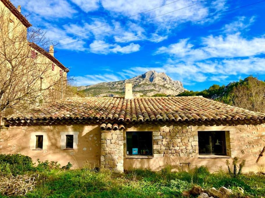 uma antiga casa de pedra com uma montanha ao fundo em Maison à Aix en provence au pied de la Sainte Victoire em Beaurecueil