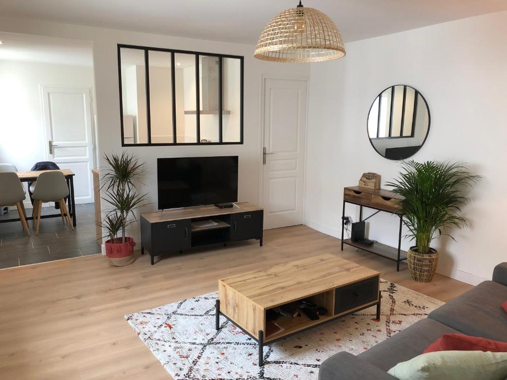 uma sala de estar com um sofá e uma televisão em Appartement T2 lumineux et cosy au calme proche du centre avec TV Netflix et Wifi em La Rochelle