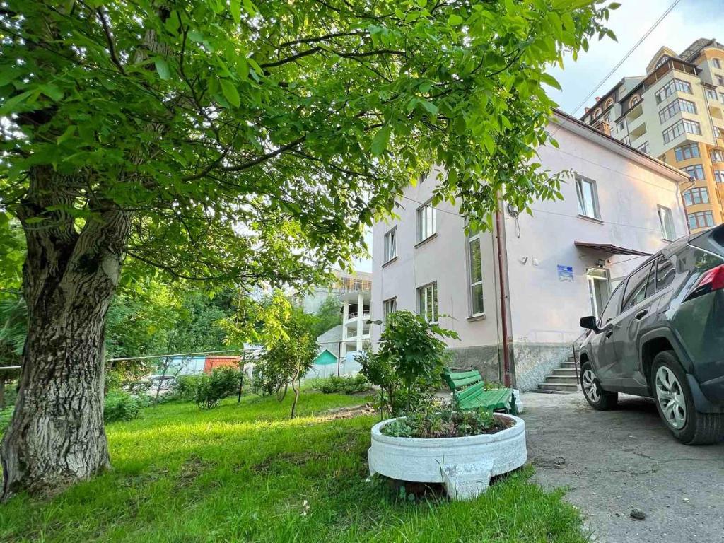Un árbol y un coche estacionados al lado de un edificio en Готель-хостел en Truskavets