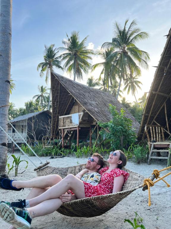 dos mujeres tumbadas en una hamaca en una playa en Kanipa Beach Glamping, en El Nido