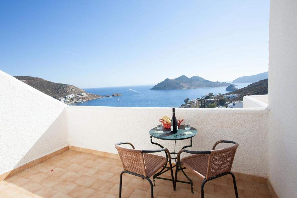 a table and chairs on a balcony with a view of the ocean at Golden Sun Hotel Patmos in Patmos