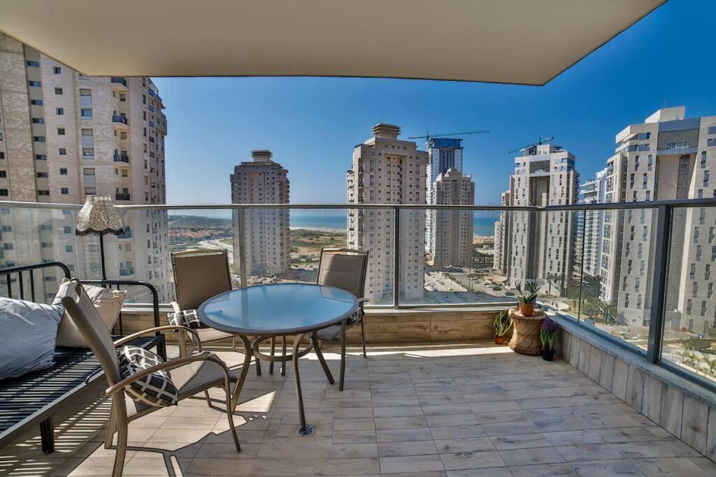 balcón con mesa, sillas y vistas a la ciudad en Стильные апартаменты Dotan, en Netanya