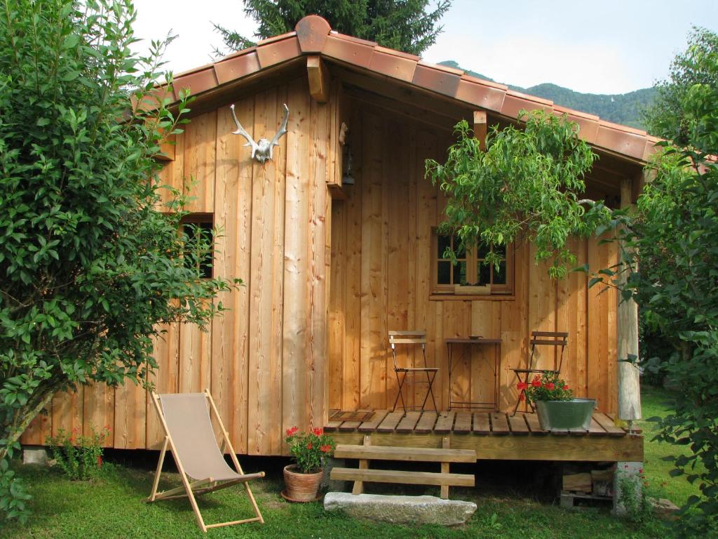 cobertizo de madera con sillas, mesa y banco en La Cabane du Trappeur, en Ore