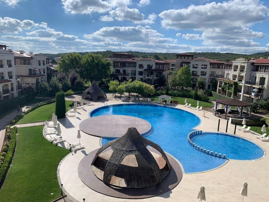 a large pool with an umbrella and chairs and buildings at Green Life Beach Resort Private Studio Flat First Line Kavatsi Smokinya Beach Sozopol in Sozopol