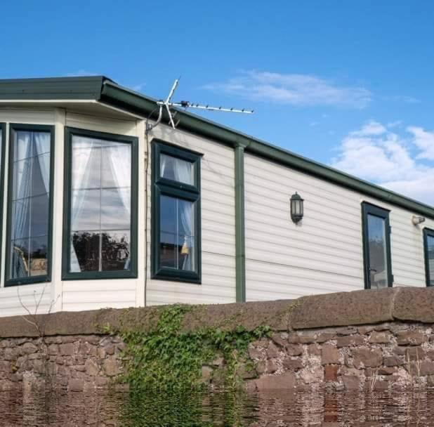 a white house with black windows and a brick wall at Wrights Retreat 4 Lunan View St Cyrus Caravan Park in Saint Cyrus