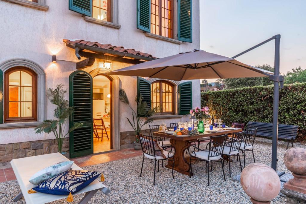 un patio avec une table, des chaises et un parasol dans l'établissement Villa Cesare 4 bedroom Villa with Pool, à Lucques