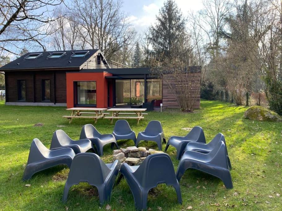 un groupe de chaises assises dans l'herbe devant une maison dans l'établissement Magnifique lodge dans la forêt de Fontainebleau, à Arbonne